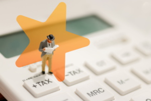 Miniature businessman on calculator buttons 'tax plus' and 'tax minus'